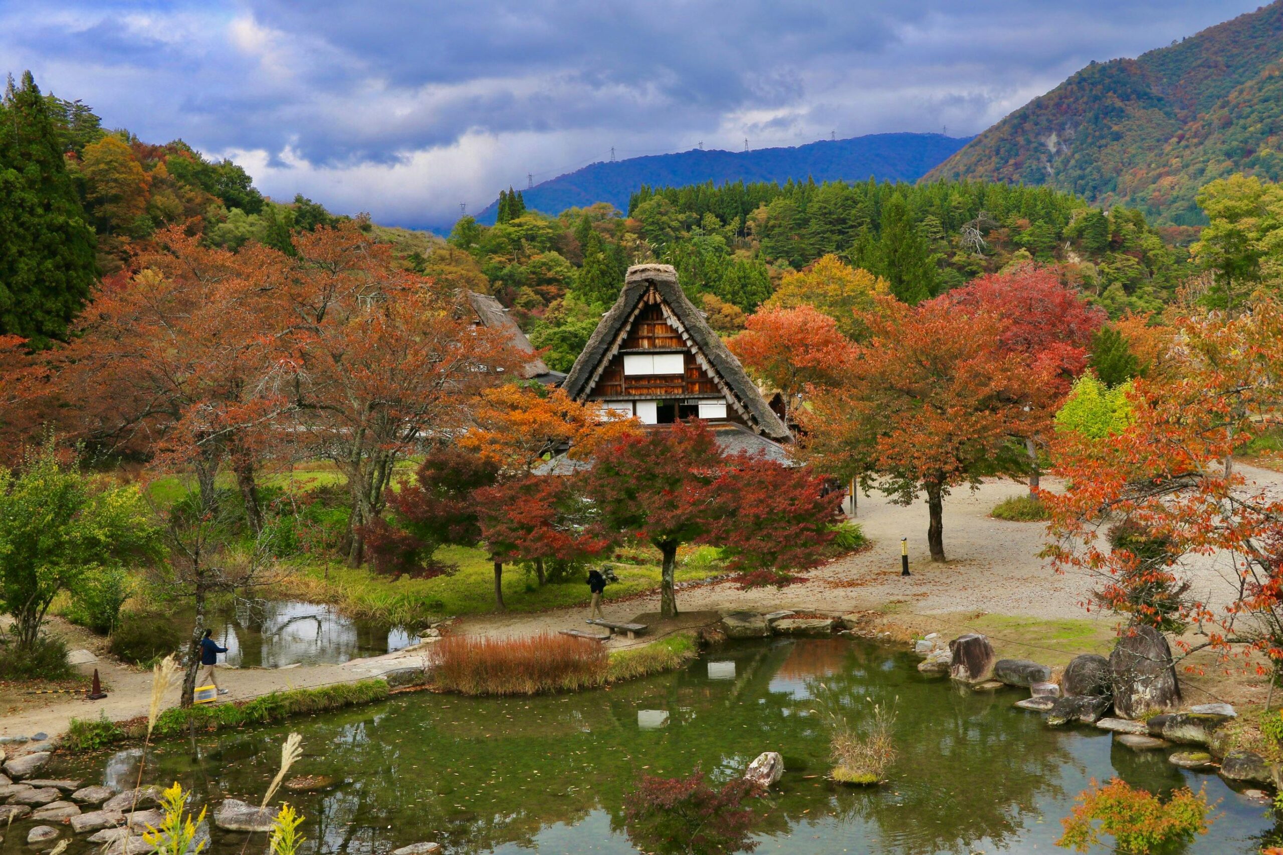 Scenic autumn view of a Gassho-zukuri house surrounded by colorful foliage in Shirakawa-go, Japan.